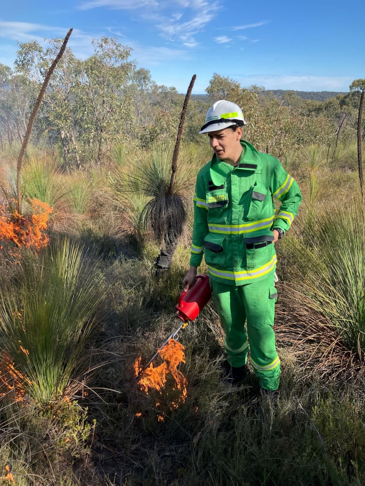 Person in helmet using drip torch